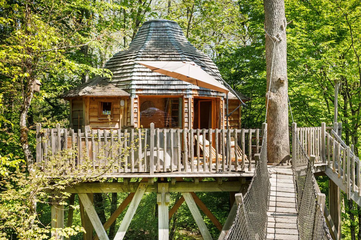 A charming tree house surrounded by trees, complete with a wooden deck