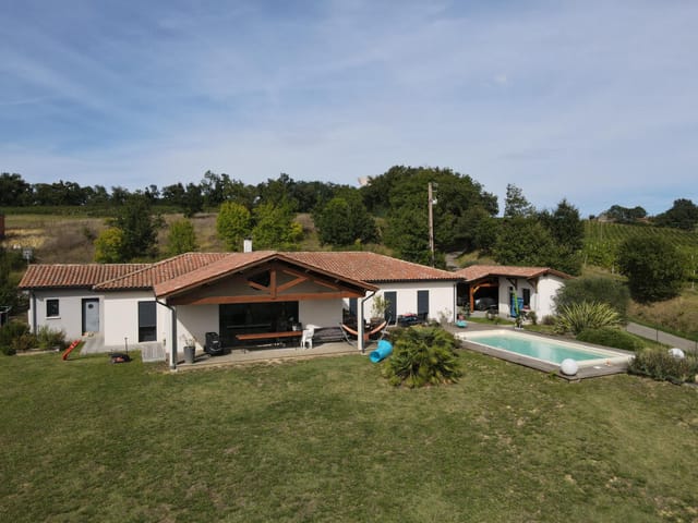 A large house surrounded by a field with a swimming pool in the center of the property
