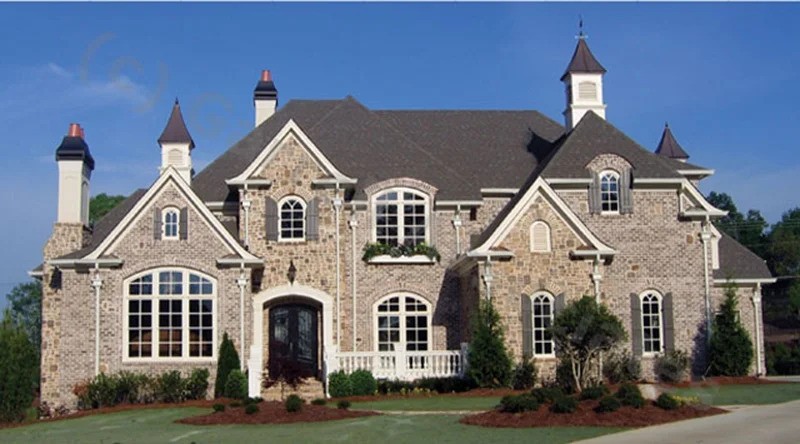 A large brick and stone house with a spacious driveway in front