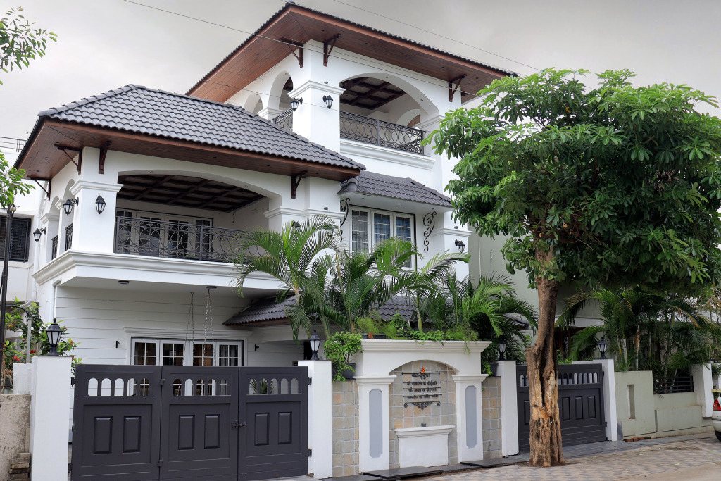 A white house with a large gate and a parked car in front
