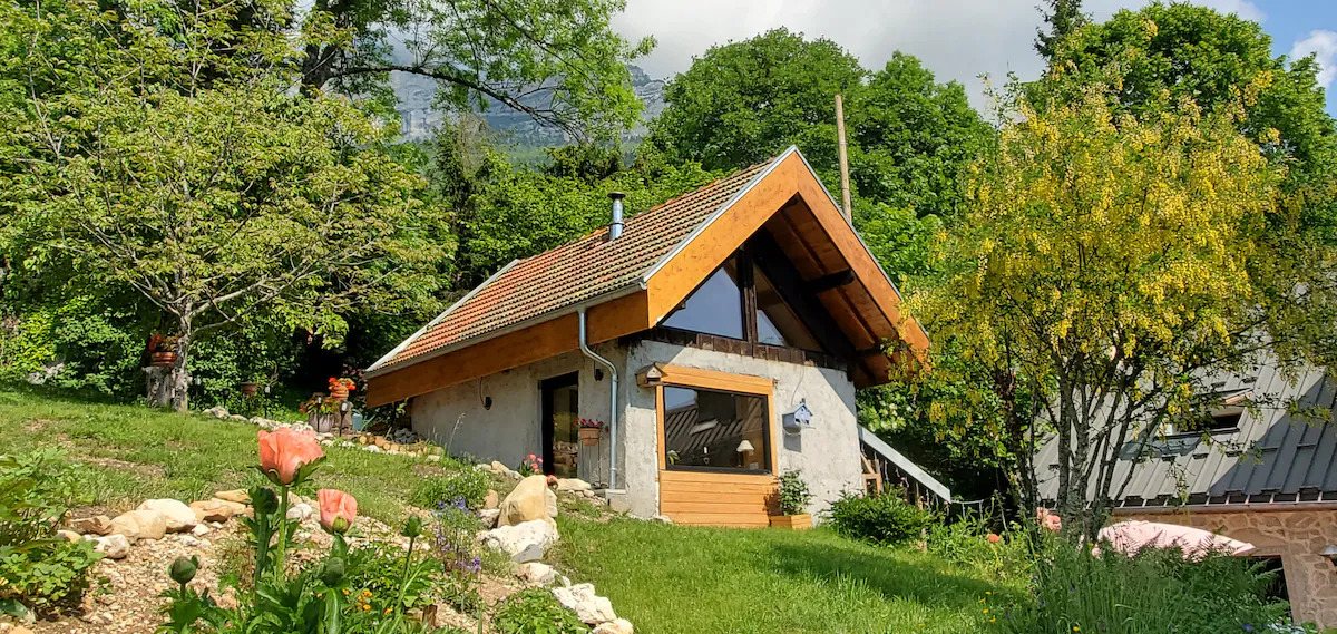 A small cabin nestled on a vibrant green hill surrounded by lush vegetation