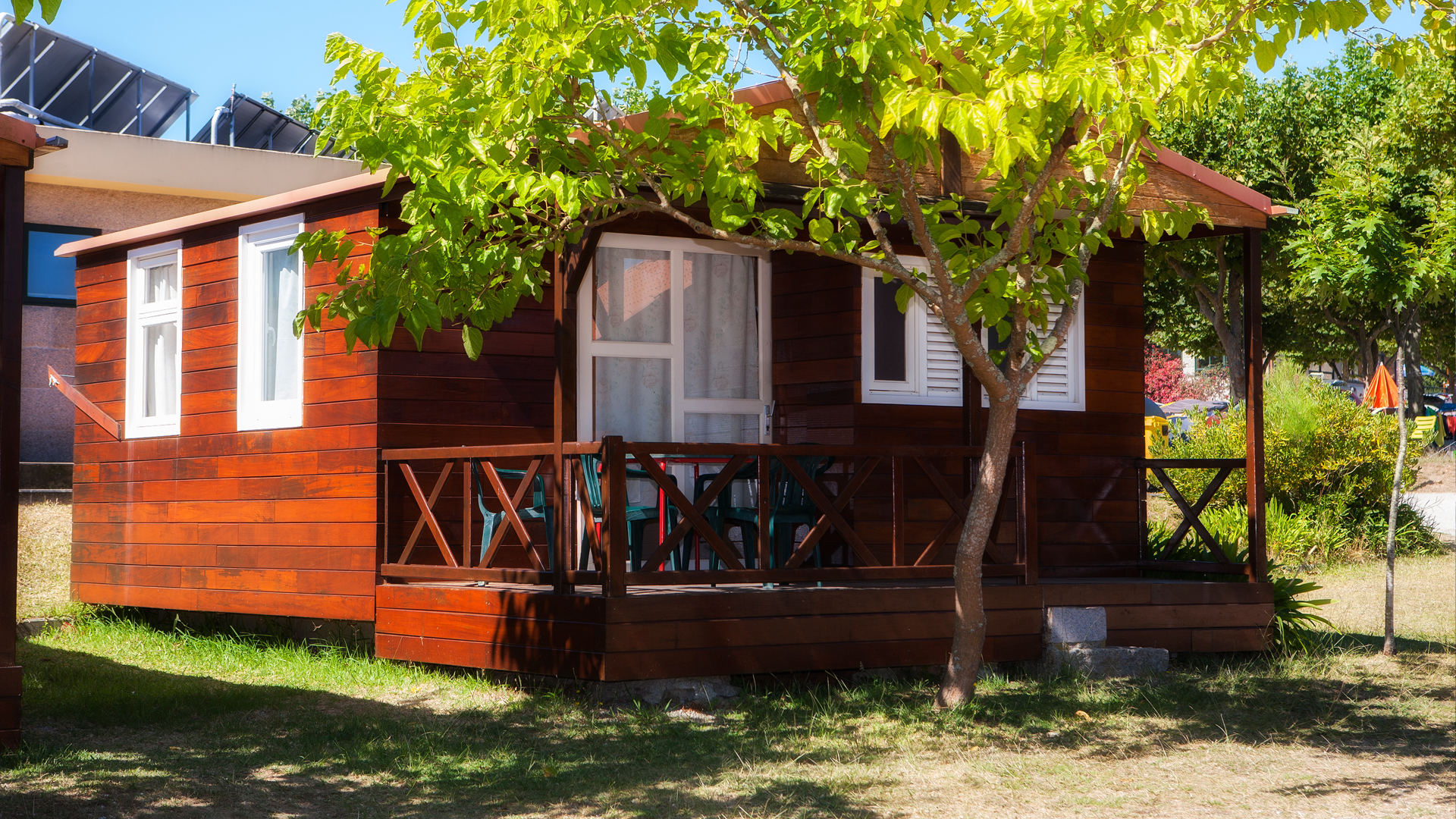 A small wooden house with a sloped roof, surrounded by greenery