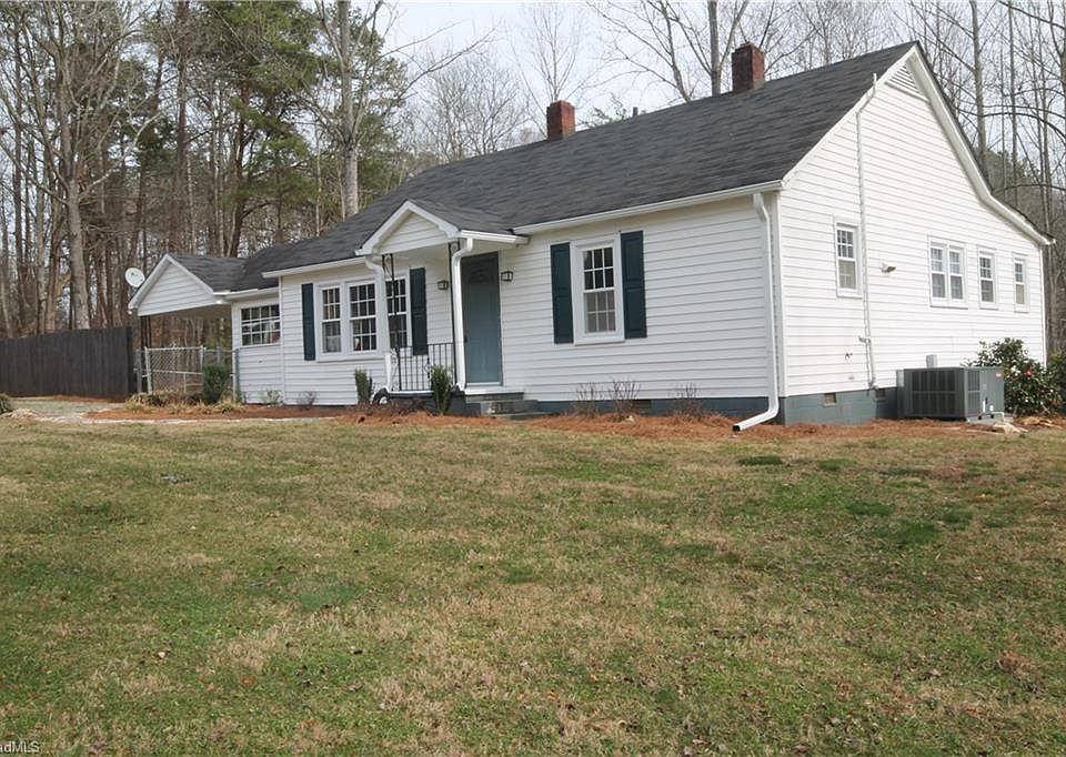 A small white house surrounded by a spacious yard