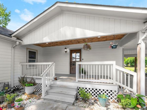 A white house featuring a porch and a wooden deck