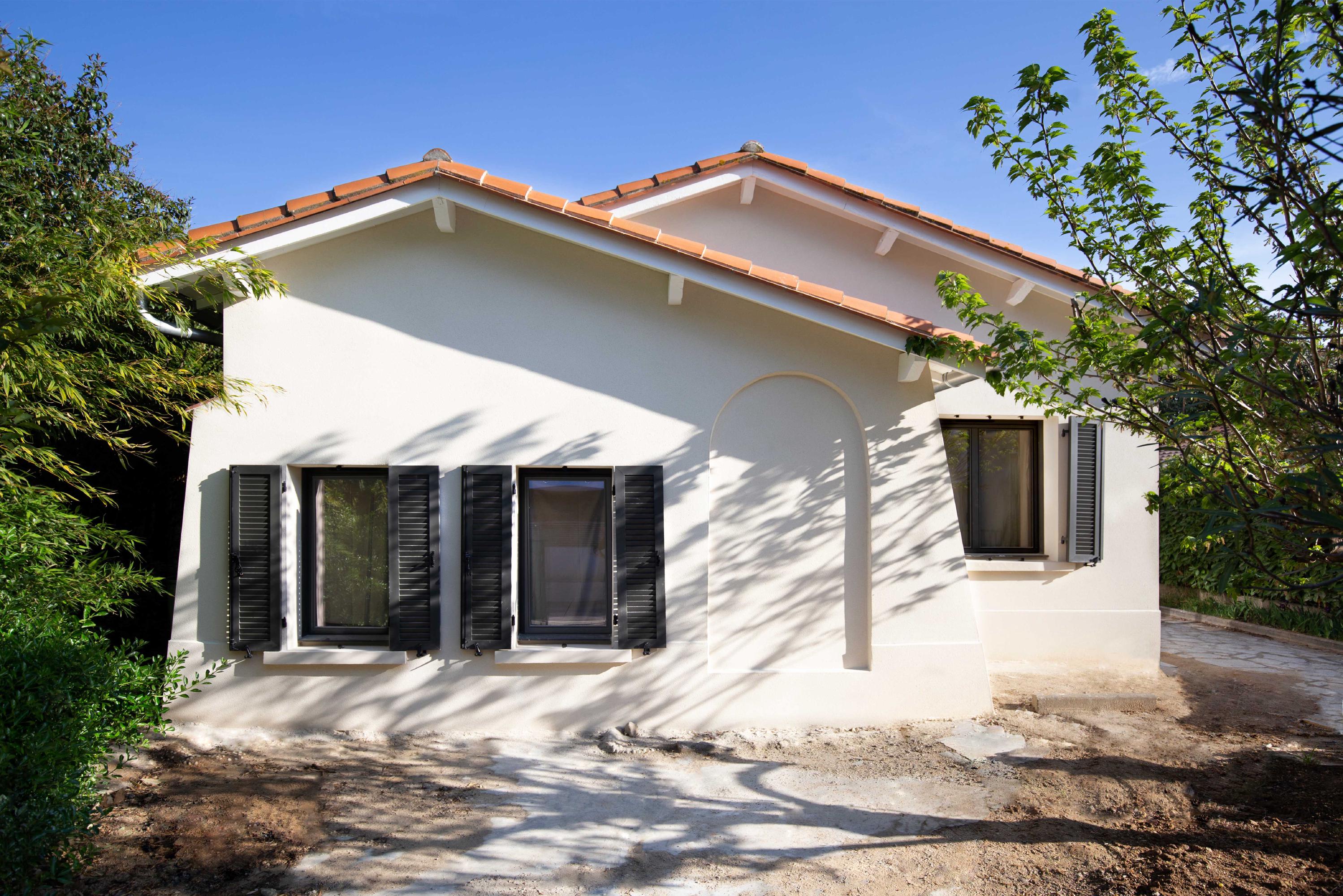 A small house featuring a white roof, set against a clear blue sky